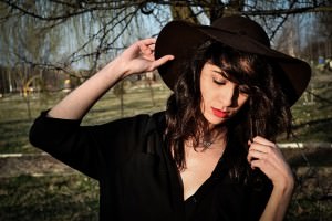 dziewczyna w czarnej tunice i brązowym kapeluszu