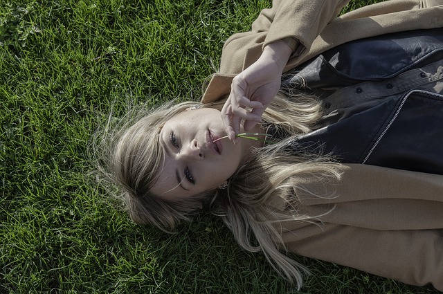 Dziewczyna w płaszczu leży na trawie