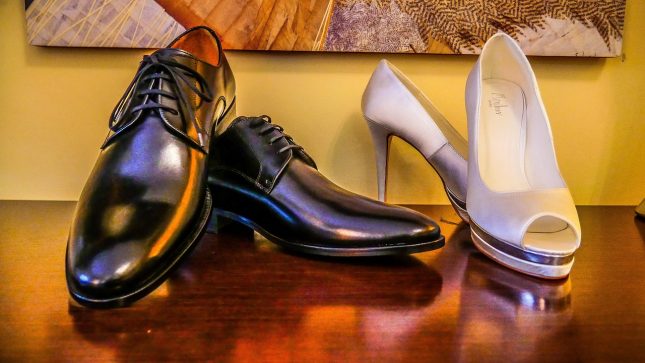 Eleganckie buty męskie i damskie szpilki ustawione obok siebie na drewnianym stole.